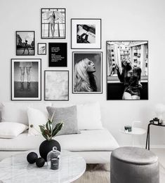 a living room filled with white furniture and pictures on the wall above it's coffee table