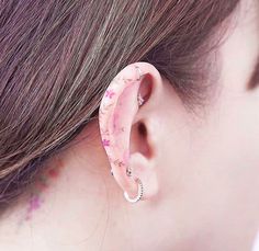 a close up of a person's ear wearing a pink marbled earring