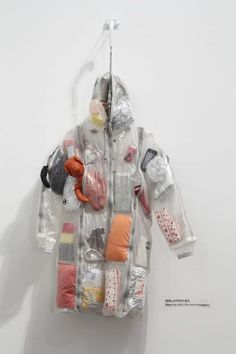 a plastic bag filled with lots of items hanging on a wall next to a white wall