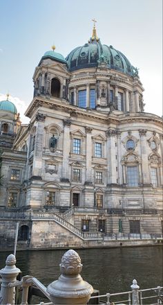 a large building with a dome on top next to a body of water in front of it