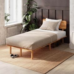 a bed sitting on top of a wooden floor next to a plant in a room