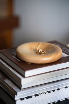 a stack of books sitting on top of each other next to a wooden ring dish