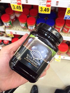 a hand holding a jar of jelly in a store