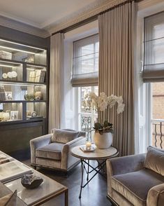 a living room filled with lots of furniture next to a window covered in bookshelves