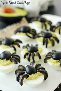 deviled eggs decorated with black spider legs on a white platter, ready to be eaten