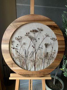 a wooden frame with flowers painted on the front and side, sitting next to a potted plant