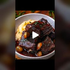 a bowl filled with meat and potatoes on top of a table