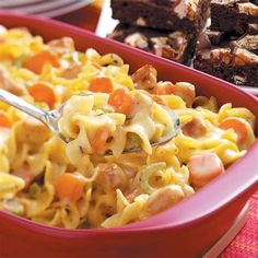 a red bowl filled with macaroni and cheese next to brownies