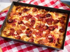 a square pizza with pepperoni and cheese on a red and white checkered tablecloth