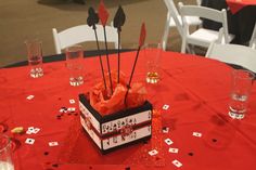 a red table cloth topped with a black and white box filled with arrows next to glasses