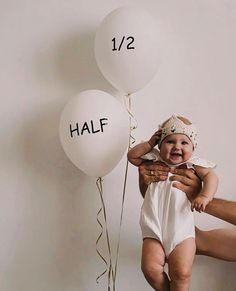 a man holding a baby in front of balloons with the word half written on them