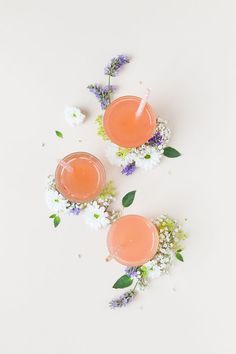 two glasses filled with drinks sitting next to flowers