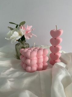 two pink candles sitting next to each other on a white cloth