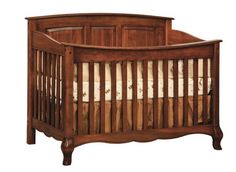 a wooden crib with white sheets on it