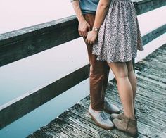 a man and woman standing on a dock next to each other with their arms around each other