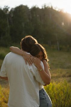 two people embracing each other in a field