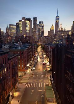 an empty city street at night with tall buildings and skyscrapers in the back ground