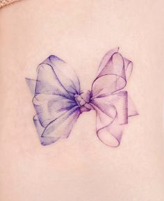 a woman's stomach with a purple bow tattoo on it