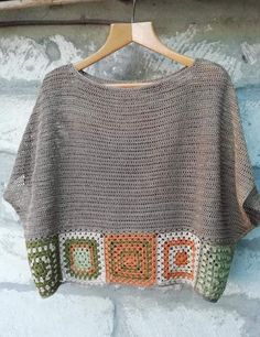 a crocheted sweater hanging on a wooden hanger