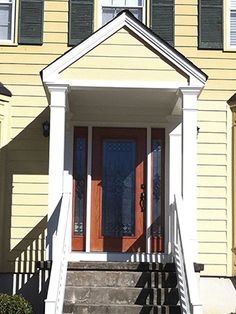 a yellow house with red front door and steps