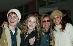 three women and one man are posing for the camera with their arms around each other