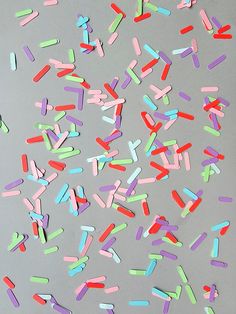 multicolored confetti sprinkles are scattered on a gray surface