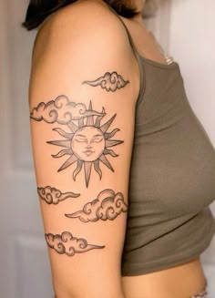 a woman with a sun and clouds tattoo on her left arm, showing it's upper half