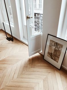 an open door with a picture frame on the floor in front of it next to a window