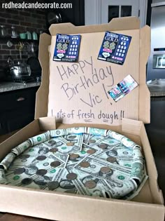 a birthday cake in a box with money on it