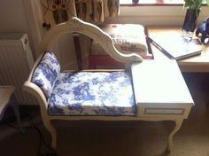 a white chair sitting next to a desk with a blue and white cushion on it