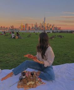 a woman sitting on top of a blanket eating pizza