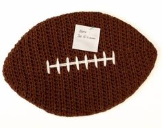 a crocheted football with a white stitch on the side and a name tag attached to it