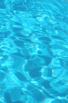 the blue water is reflecting light on it's surface and ripples in the pool