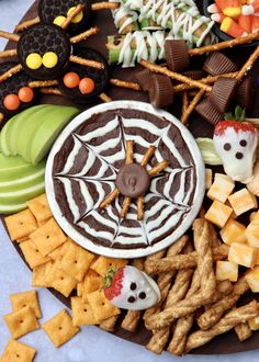 an assortment of halloween treats on a platter with candy and crackers in the background