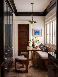 a dining room table and bench in front of a wooden door with two large windows