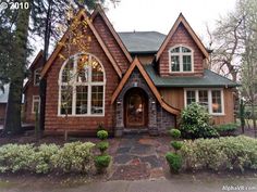 a large brown house with two windows and a stone walkway in front of the house