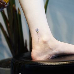 a woman's foot with a small flower tattoo on her left ankle and right leg