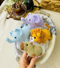 a hand holding a crocheted stuffed animal in front of several other knitted animals