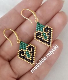 two pairs of beaded earrings in gold and green with an arrow on each ear