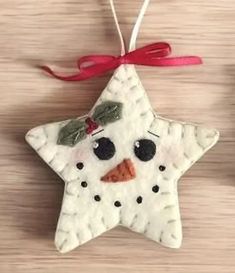 a white ceramic star ornament with a red ribbon hanging from it's side