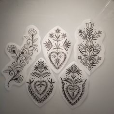 four decorative stickers with flowers and hearts on the back of each one in black ink