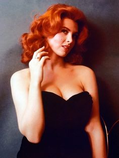 a woman with red hair is posing for a photo in a black strapless dress