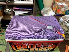 a suitcase sitting on top of a table covered in wrapping paper and other items next to a desk