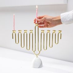 a person lighting candles on a hanukkah menorah with five candles