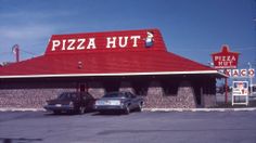 two cars parked in front of a pizza hut