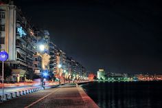 a city street at night with lights reflecting off the water and buildings on both sides