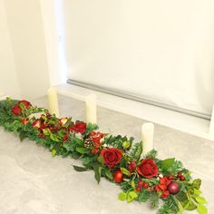 a long row of candles decorated with red flowers and greenery