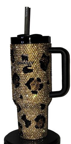 a black and gold coffee cup with leopard print on the side, sitting on a stand