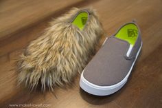 a pair of gray slippers with furry fur on the soles are sitting on a wooden floor