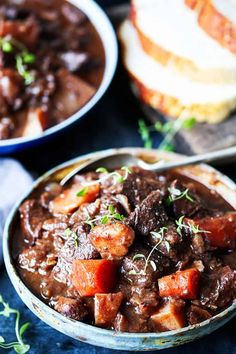 two bowls filled with beef stew and bread